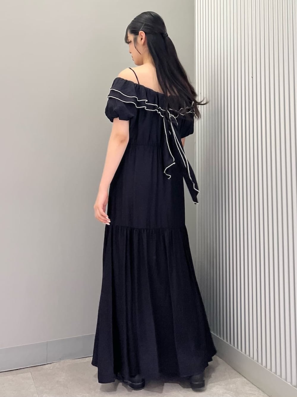 ホワイト系のショルダーバッグ、ブラック系のワンピース、ブラック系のパンプスを着用したレディースの夏コーディネートの3枚目の写真