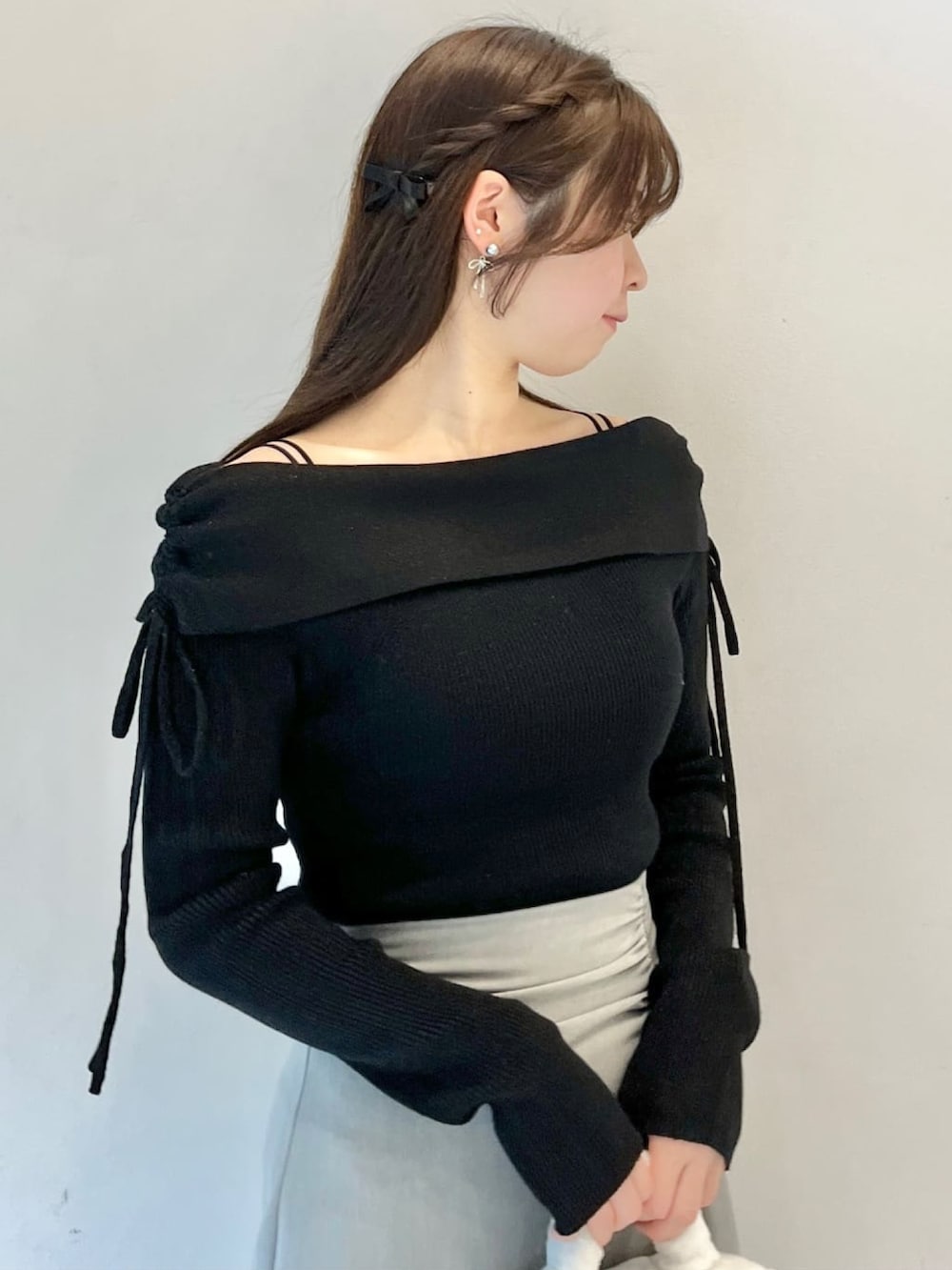 ブラック系のニット/セーター、グレー系のスカート、ホワイト系のショルダーバッグを着用したレディースの冬コーディネートの3枚目の写真