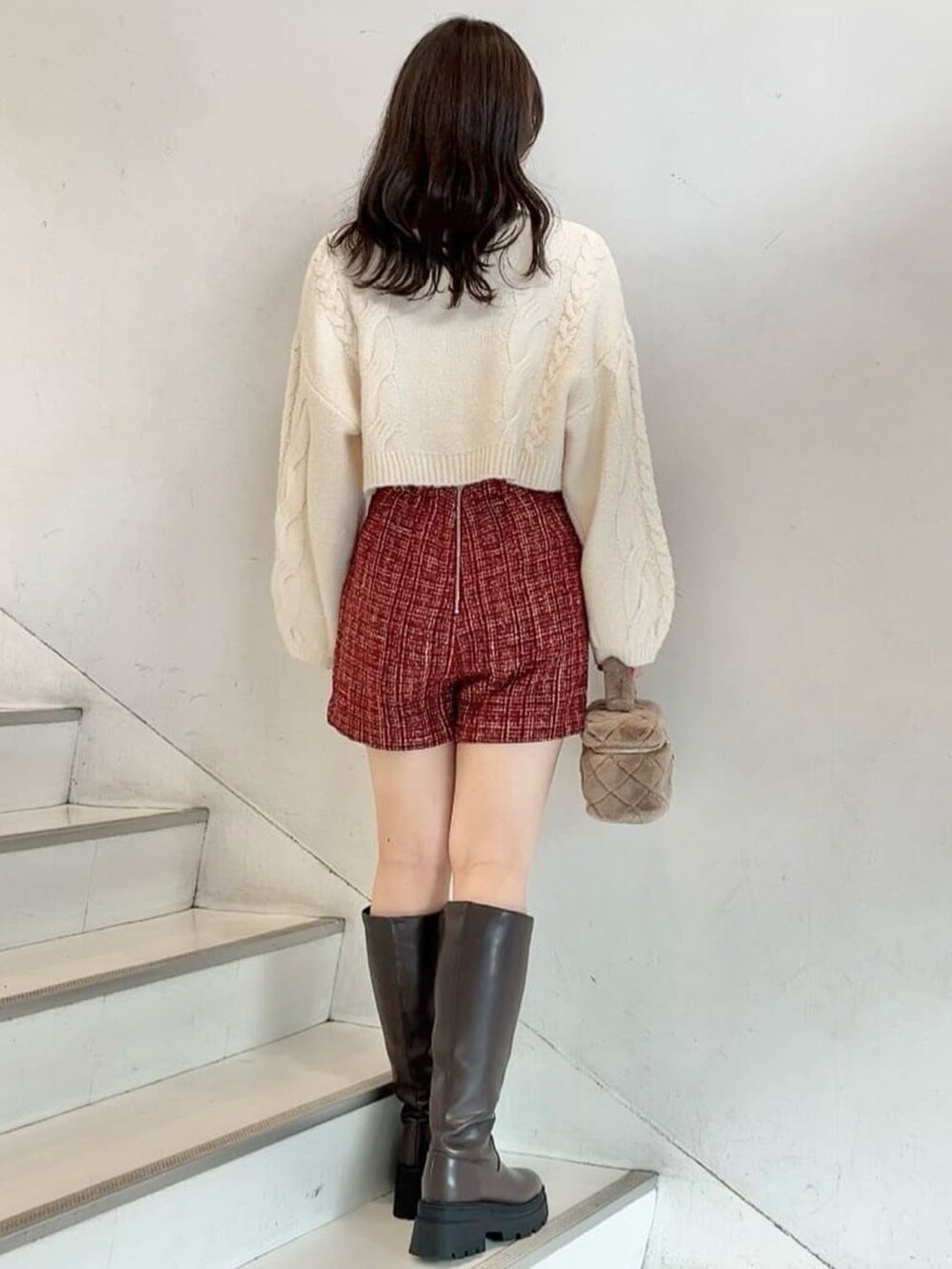 ホワイト系のニット/セーター、レッド系のスカート、ホワイト系のショルダーバッグを着用したレディースの冬コーディネートの2枚目の写真