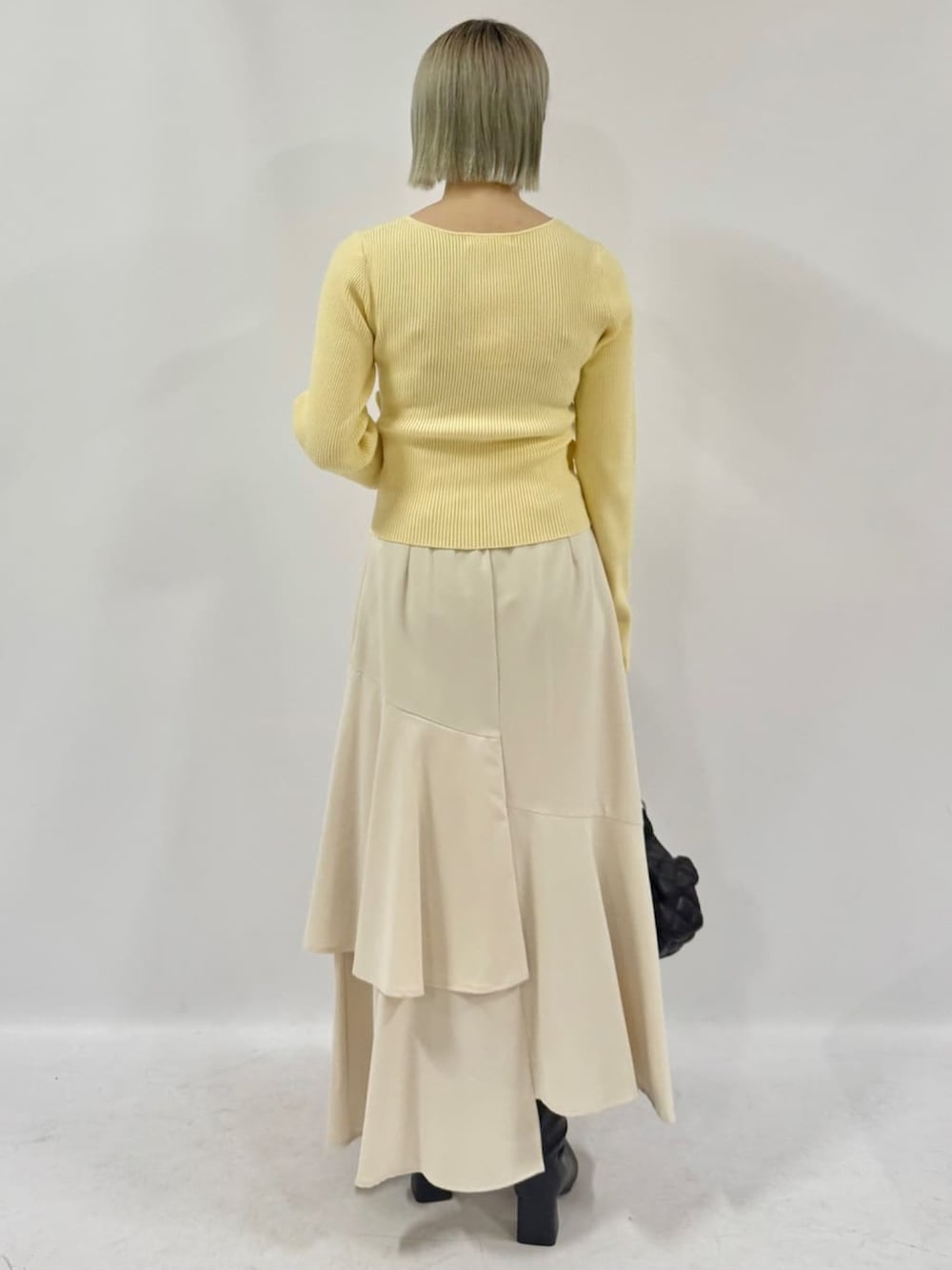 イエロー系のニット/セーター、ホワイト系のスカートを着用したレディースの冬コーディネートの3枚目の写真