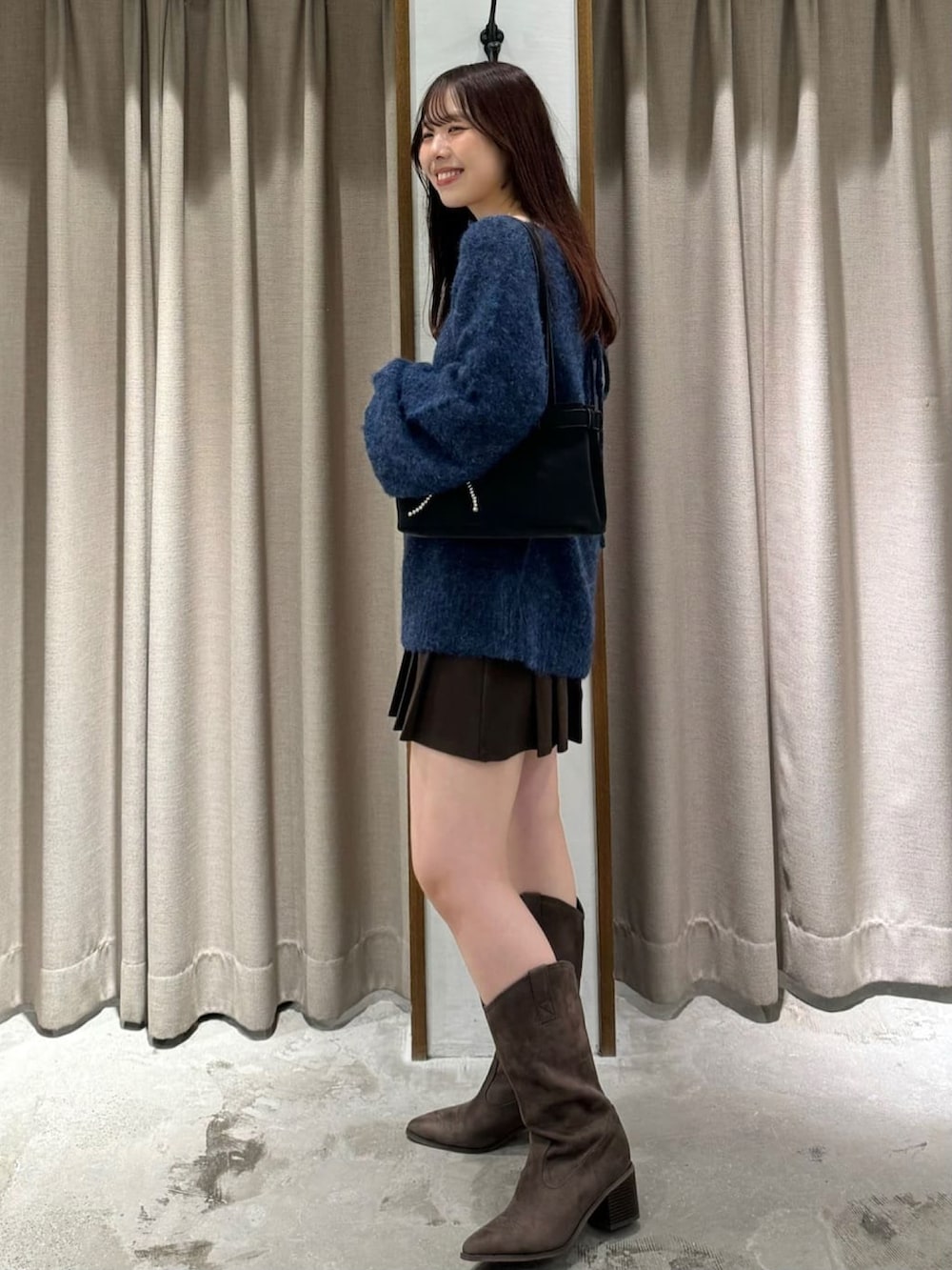 ブルー系のニット/セーター、ブラウン系のスカート、イエロー系のブーツを着用したレディースの秋コーディネートの2枚目の写真