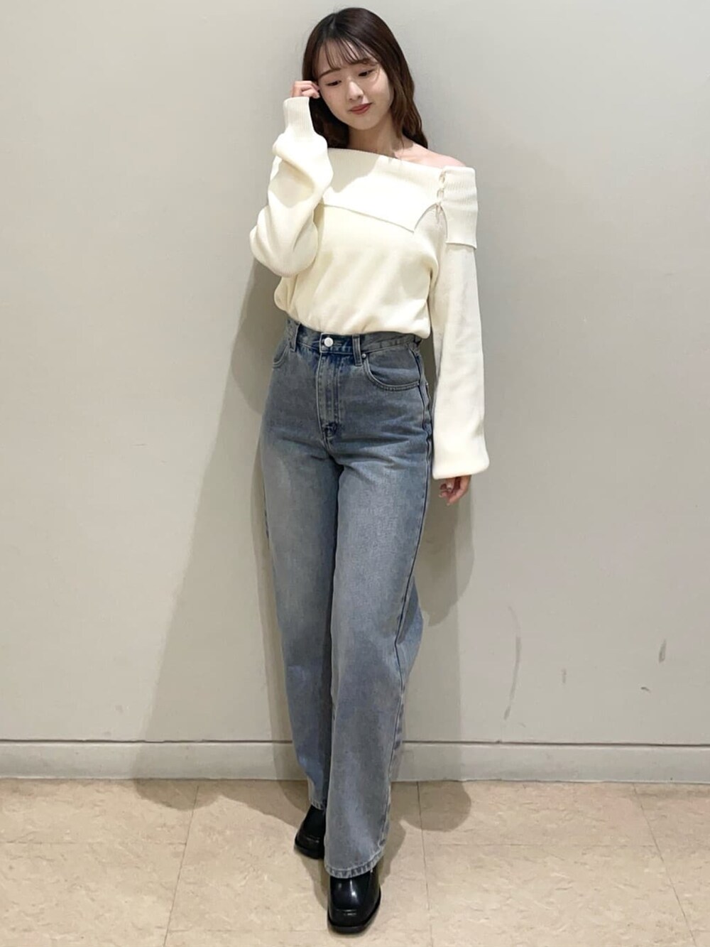 ブルー系のデニムパンツ、ホワイト系のニット/セーター、ブラック系のショルダーバッグを着用したレディースの冬コーディネートの2枚目の写真