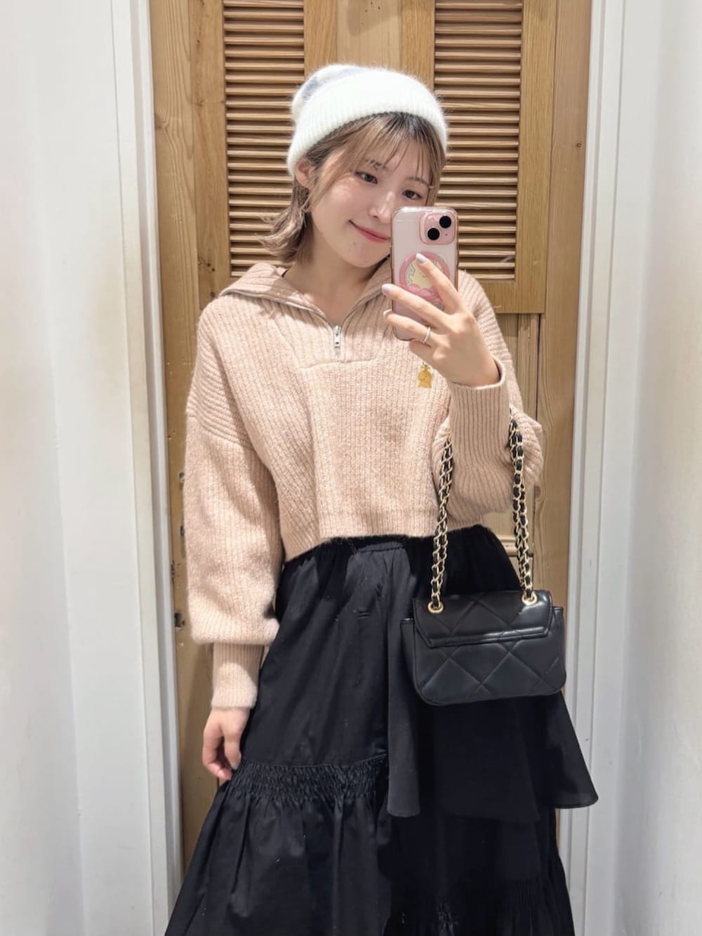 レッド系のショルダーバッグ、ブラック系のスカート、オレンジ系のニット/セーターを着用したレディースの冬コーディネートの2枚目の写真