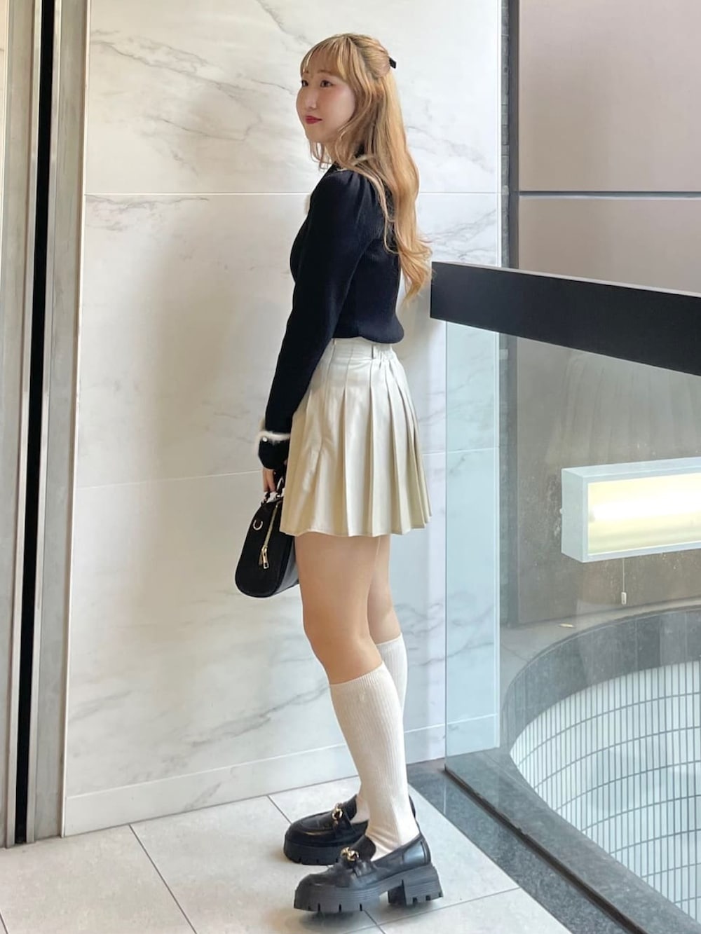 ブラック系のニット/セーター、ホワイト系のスカート、ブラック系のボストンバッグを着用したレディースの冬コーディネートの2枚目の写真