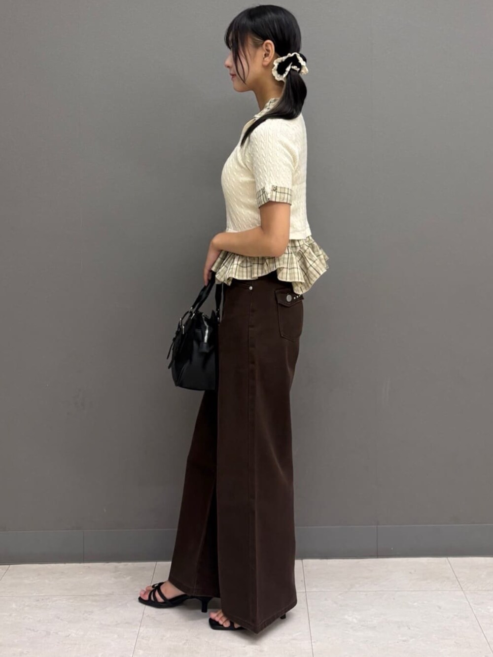 ブラウン系のデニムパンツ、ホワイト系のニット/セーター、ブラック系のショルダーバッグを着用したレディースの夏コーディネートの2枚目の写真