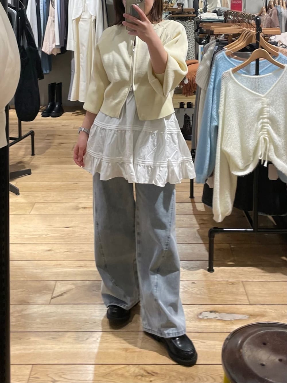 ホワイト系のニット/セーター、ブルー系のデニムパンツ、ホワイト系のスカートを着用したレディースの冬コーディネートの2枚目の写真