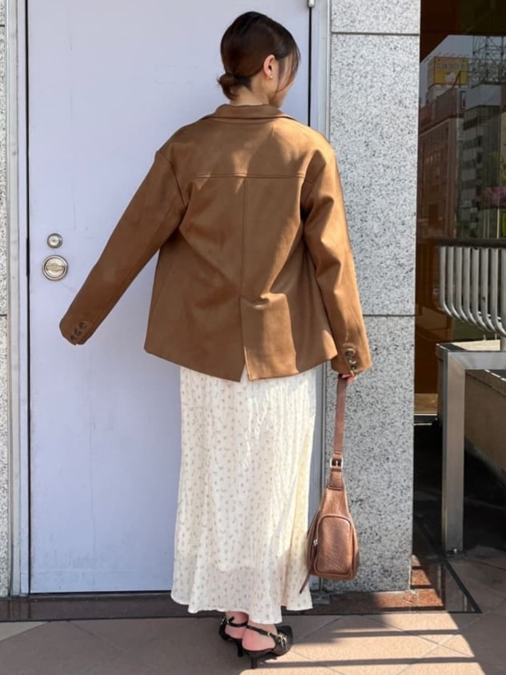 イエロー系のテーラードジャケット、ホワイト系のワンピース、ブラウン系のハンドバッグを着用したレディースの秋コーディネートの3枚目の写真