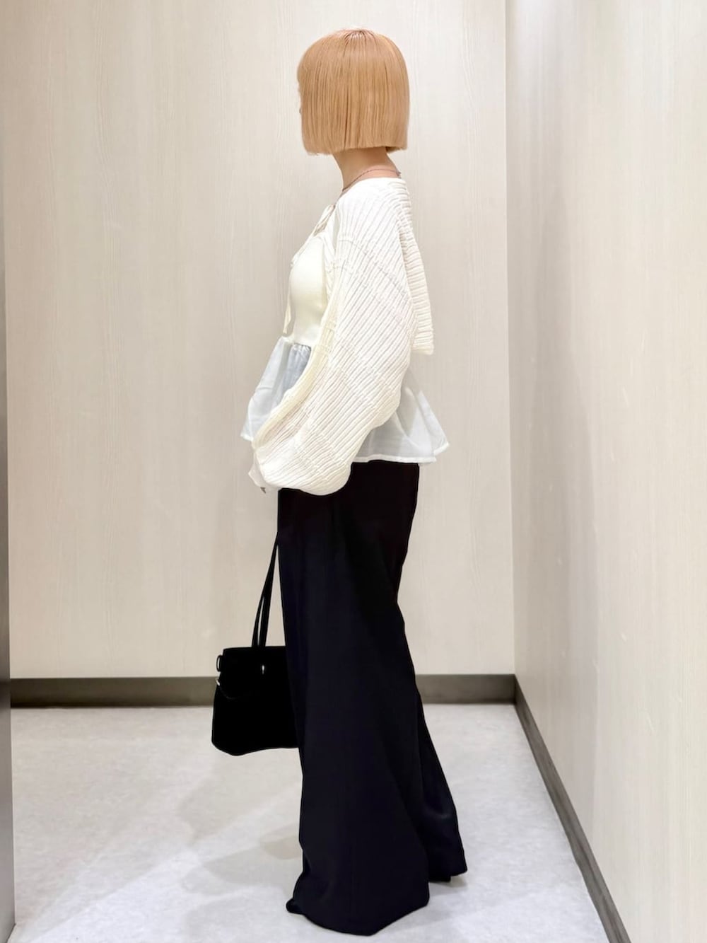 グレー系のスラックス、ブラック系のショルダーバッグ、ブラック系のパンプスを着用したレディースの秋コーディネートの2枚目の写真