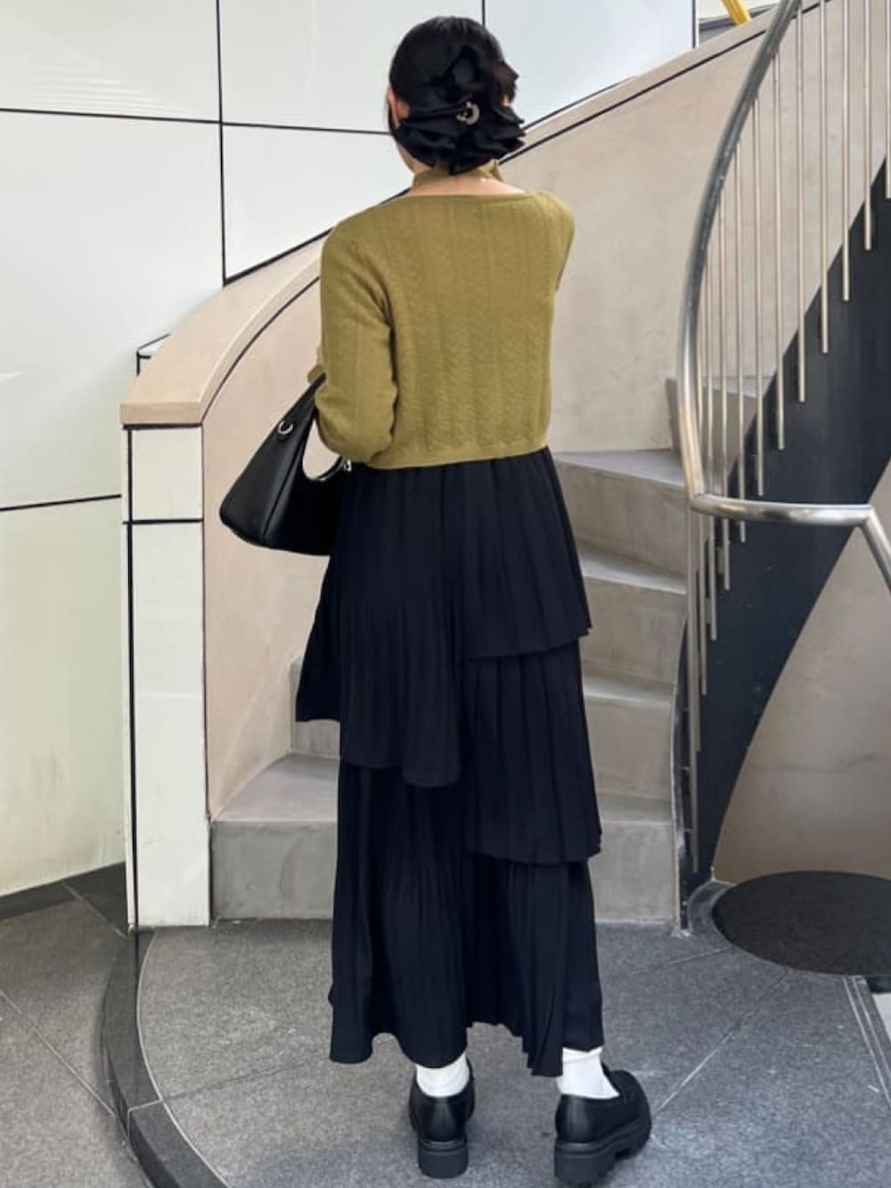 グリーン系のカーディガン/ボレロ、ブラック系のスカートを着用したレディースの秋コーディネートの2枚目の写真