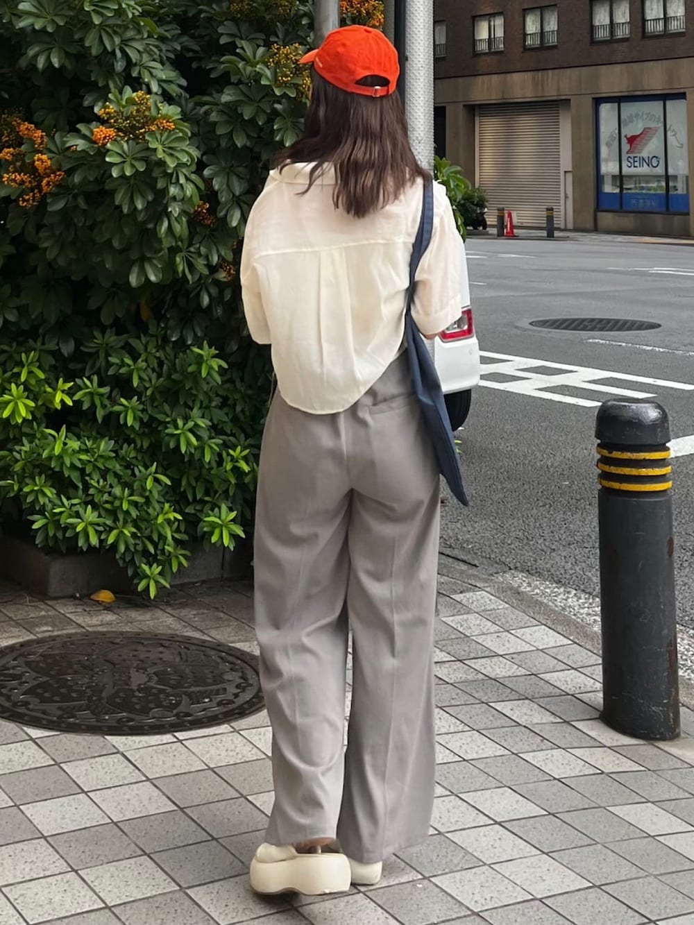 ホワイト系のシャツ/ブラウス、グレー系のスラックス、ブルー系のトートバッグを着用したレディースの夏コーディネートの2枚目の写真