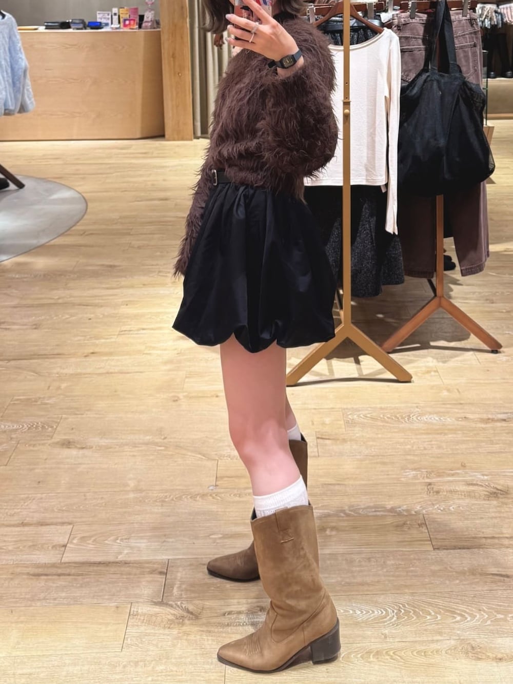 ブラウン系のニット/セーター、ブラック系のスカート、イエロー系のブーツを着用したレディースの秋コーディネートの2枚目の写真