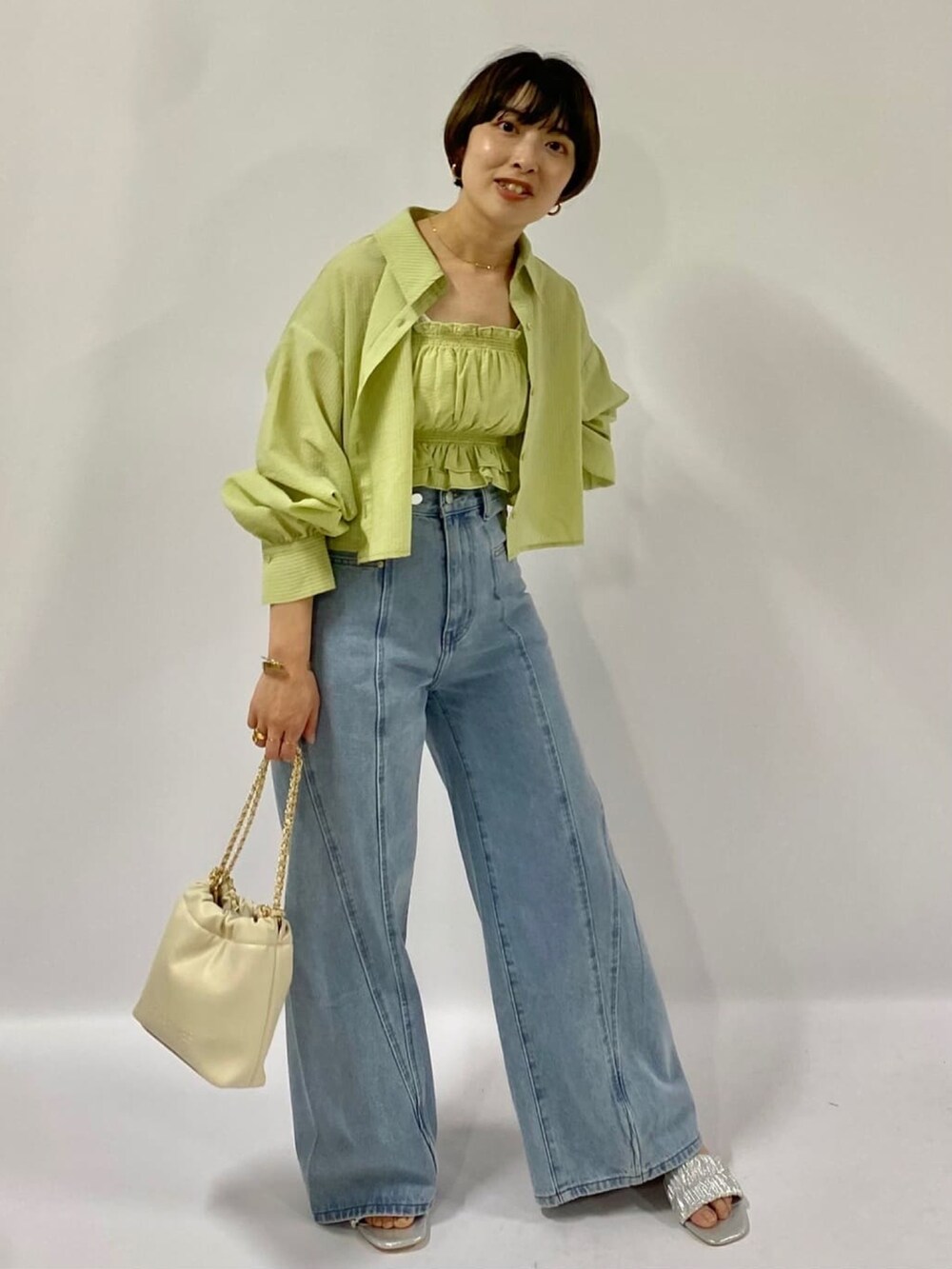 グリーン系のシャツ/ブラウス、ブルー系のデニムパンツ、ブラック系のハンドバッグを着用したレディースの夏コーディネートの2枚目の写真