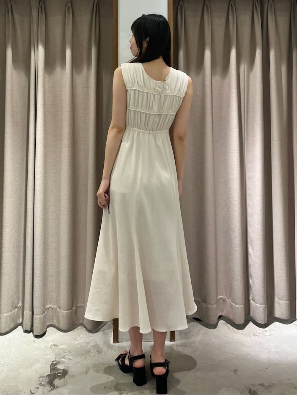 ホワイト系のワンピース、ブラック系のサンダルを着用したレディースの春コーディネートの2枚目の写真