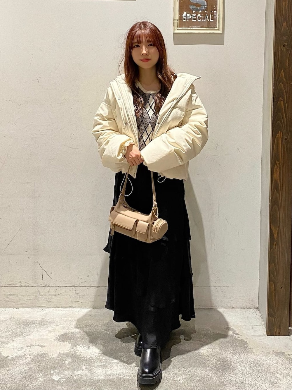 グレー系のニット/セーター、ブラック系のスカート、ホワイト系のダウンジャケット/コートを着用したレディースの冬コーディネートの2枚目の写真