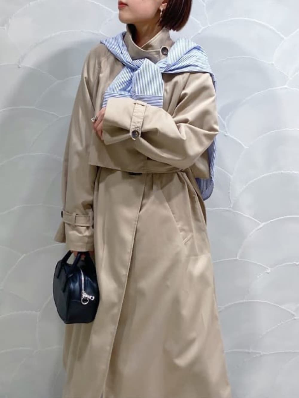 ベージュ系のトレンチコート、ブラック系のボストンバッグ、ブラック系のデニムパンツを着用したレディースの春コーディネートの2枚目の写真