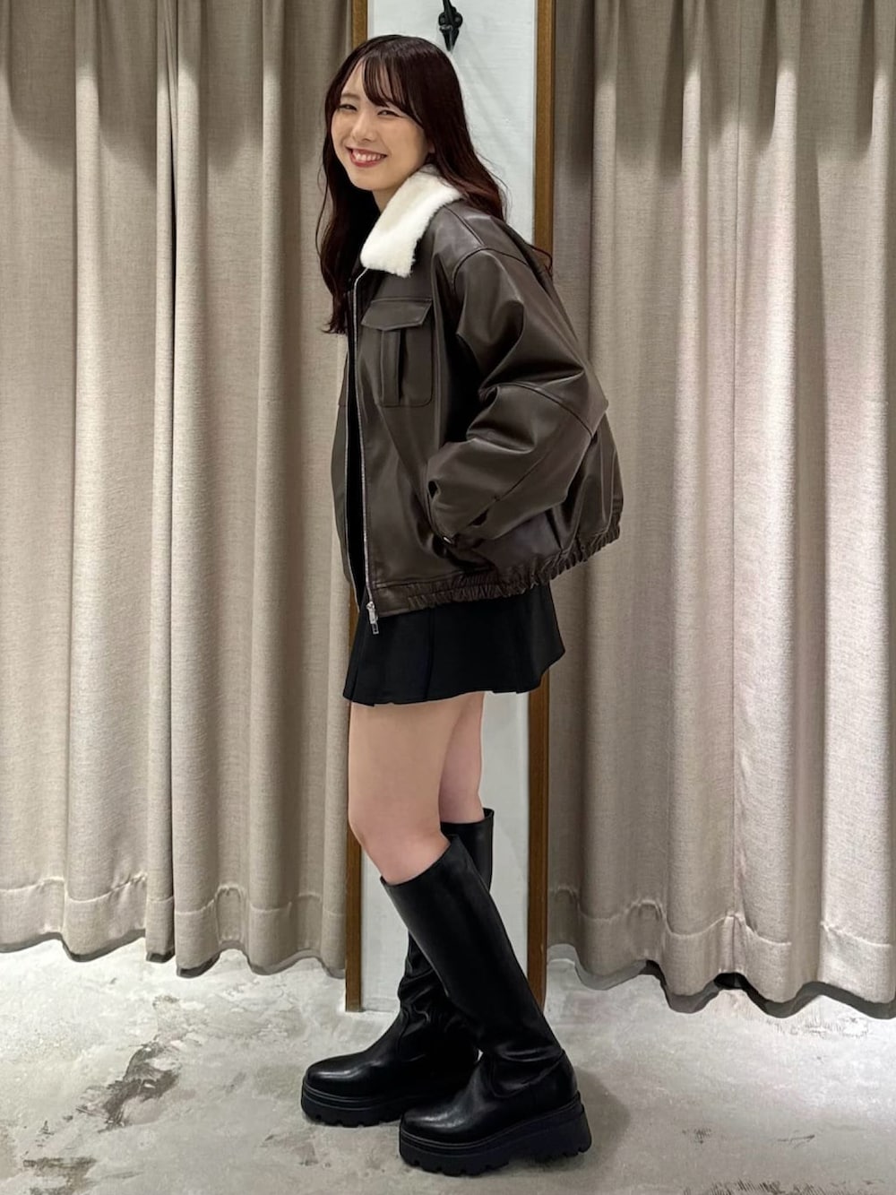 ブラウン系のブルゾン、ブラック系のスカート、ブラック系のブーツを着用したレディースの冬コーディネートの2枚目の写真