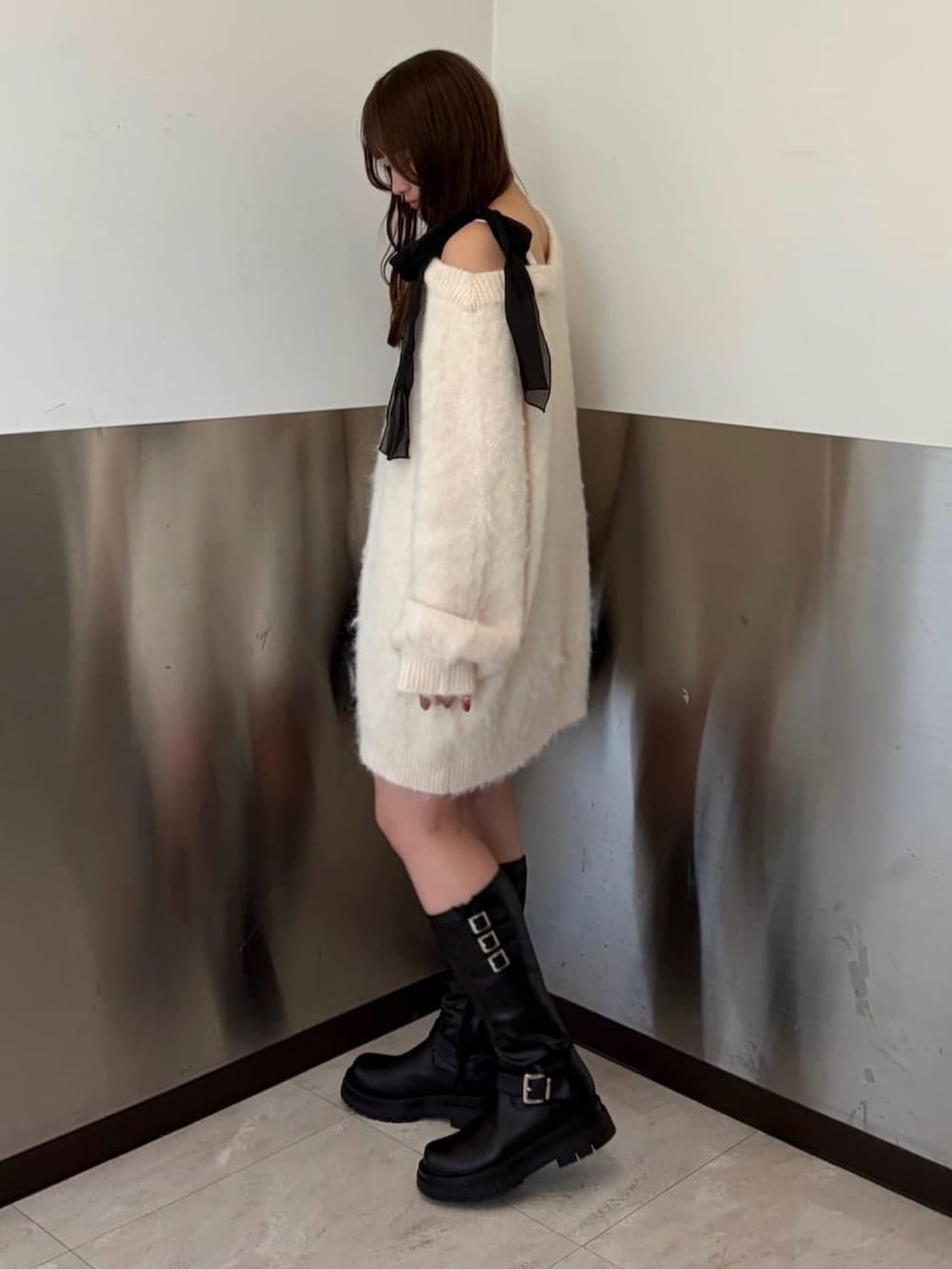 ホワイト系のチュニック、ブラック系のショルダーバッグ、ブラック系のブーツを着用したレディースの冬コーディネートの2枚目の写真