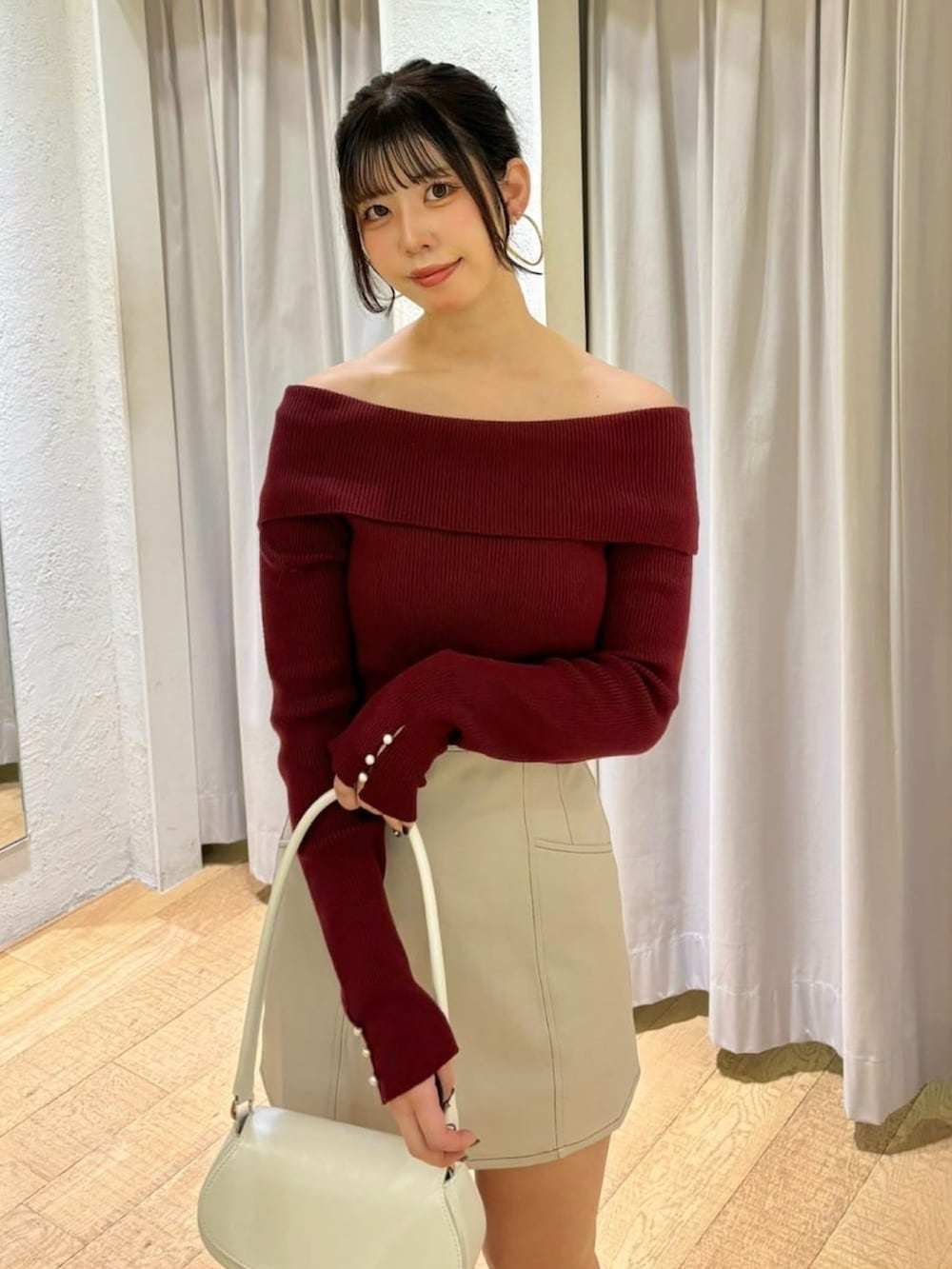 レッド系のニット/セーター、ブラック系のブーツ、ホワイト系のスカートを着用したレディースの冬コーディネートの2枚目の写真