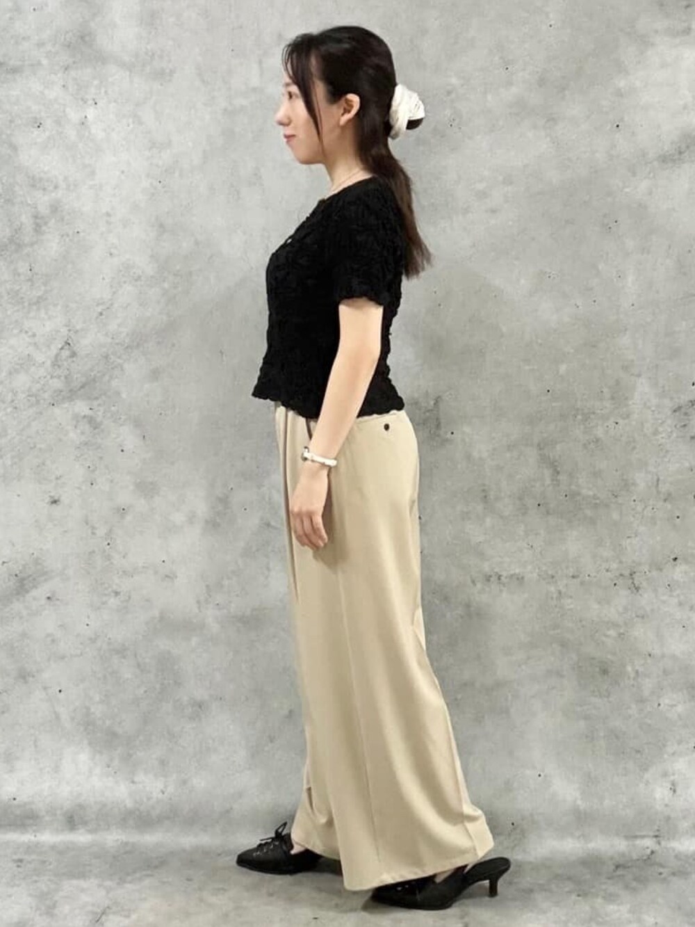 ベージュ系のスラックス、ブラック系のTシャツ/カットソー、ブラック系のパンプスを着用したレディースの夏コーディネートの2枚目の写真