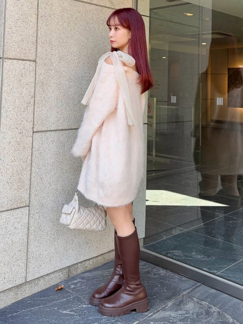 ピンク系のチュニック、ホワイト系のショルダーバッグを着用したレディースの冬コーディネートの2枚目の写真