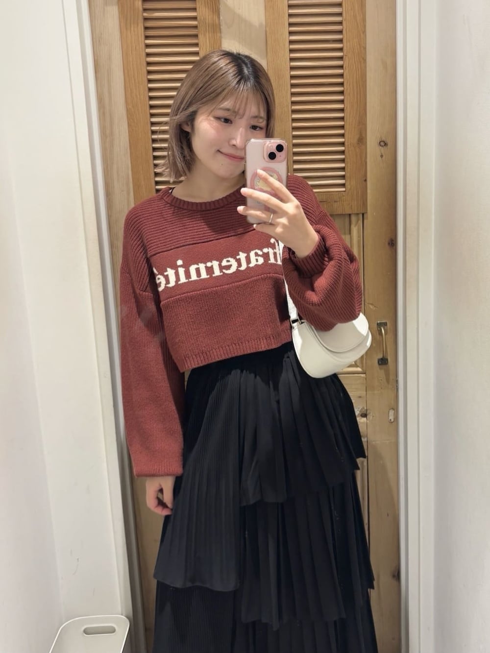 オレンジ系のニット/セーター、ブラック系のスカート、ホワイト系のマフラーを着用したレディースの冬コーディネートの3枚目の写真