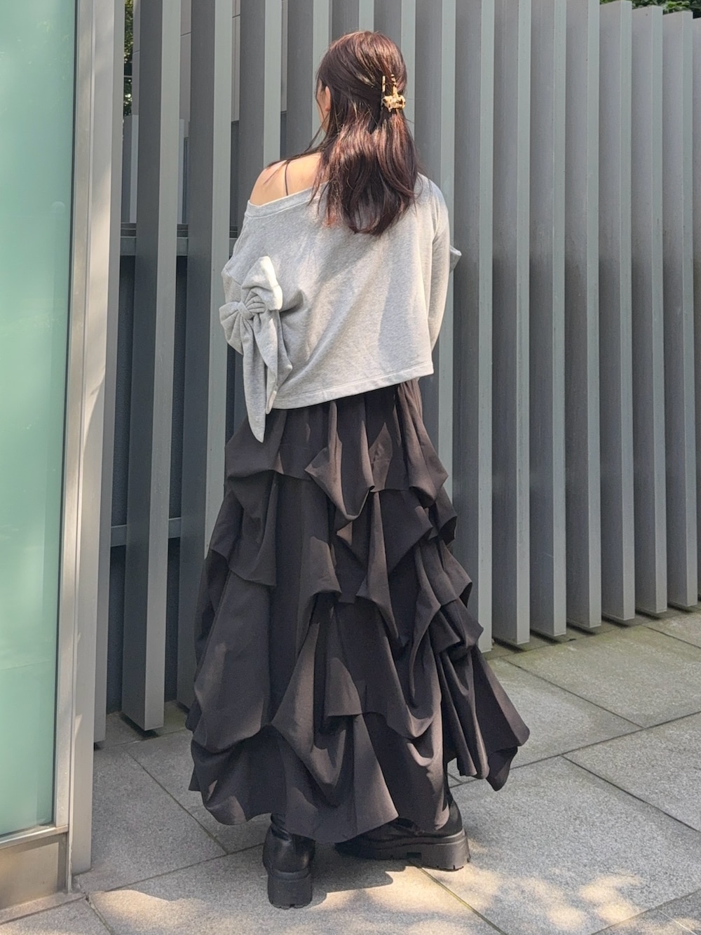 ブラック系のスカート、ブラック系のブーツ、グレー系のTシャツ/カットソーを着用したレディースの秋コーディネートの3枚目の写真