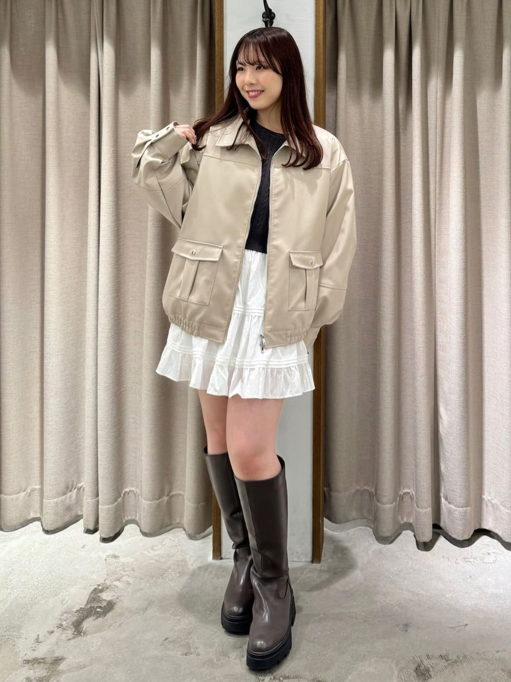 グレー系のニット/セーター、ホワイト系のブルゾン、ホワイト系のスカートを着用したレディースの冬コーディネートの2枚目の写真