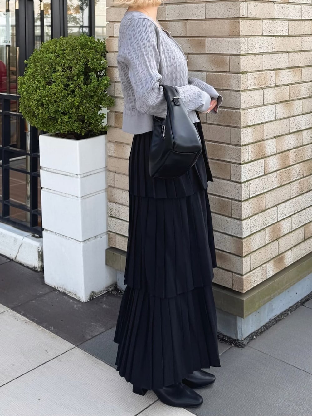 グレー系のカーディガン/ボレロ、ブラック系のスカートを着用したレディースの秋コーディネートの2枚目の写真