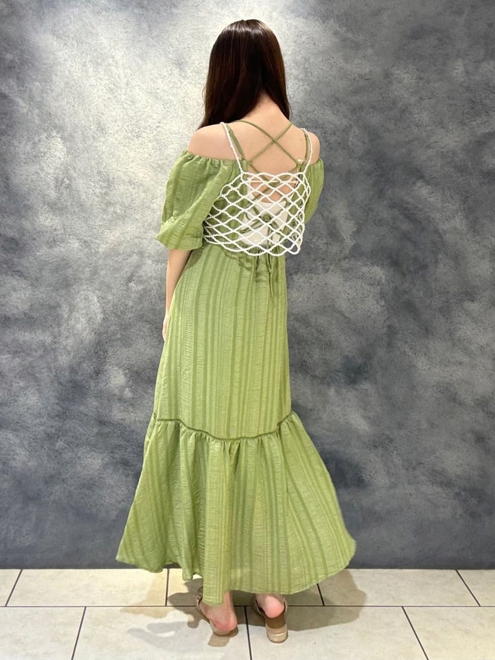 ベージュ系のベスト、グリーン系のワンピース、ゴールド系のサンダルを着用したレディースの夏コーディネートの2枚目の写真