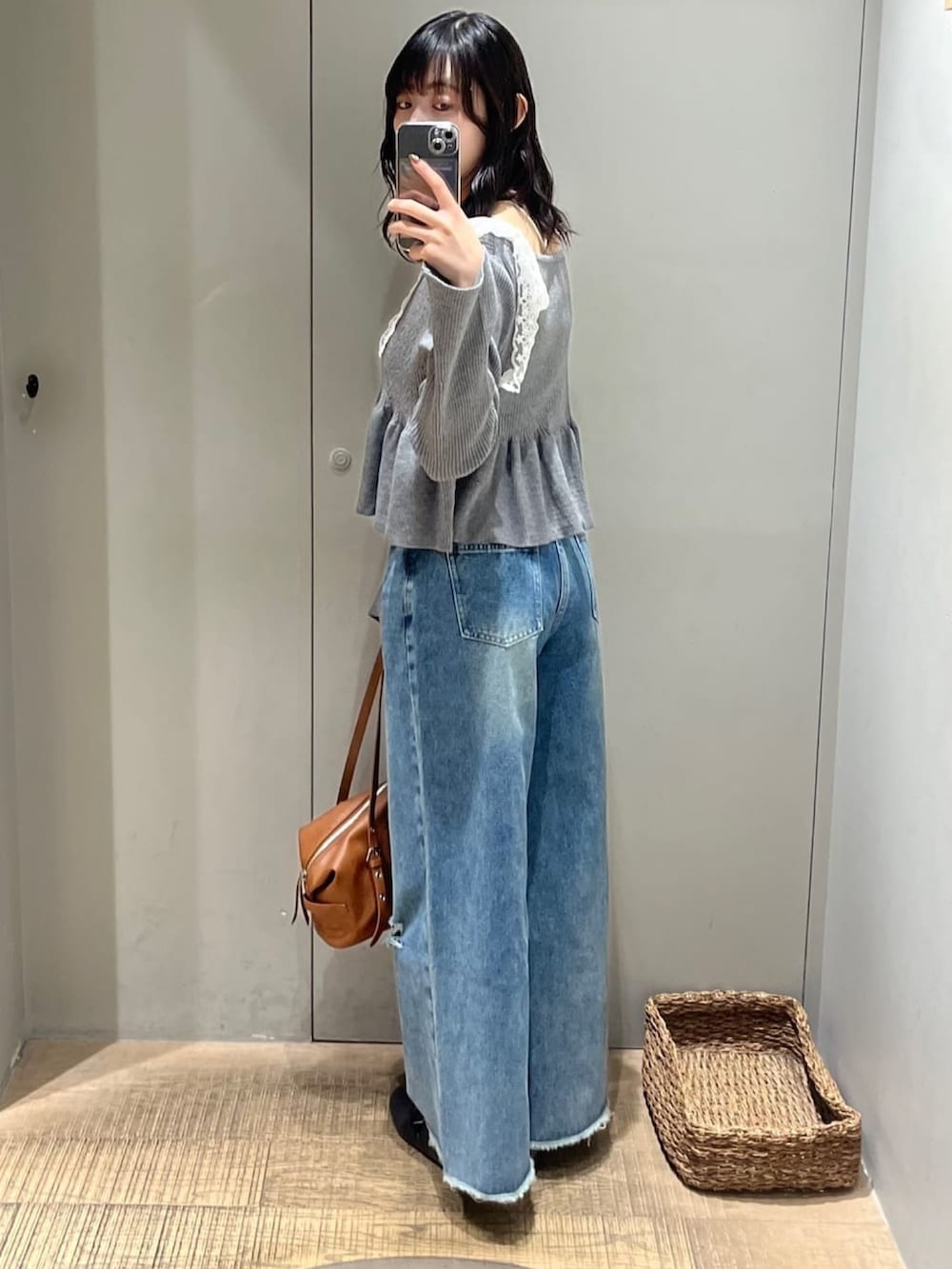 ブラウン系のボストンバッグ、グレー系のアンサンブル、ブルー系のデニムパンツを着用したレディースの秋コーディネートの3枚目の写真