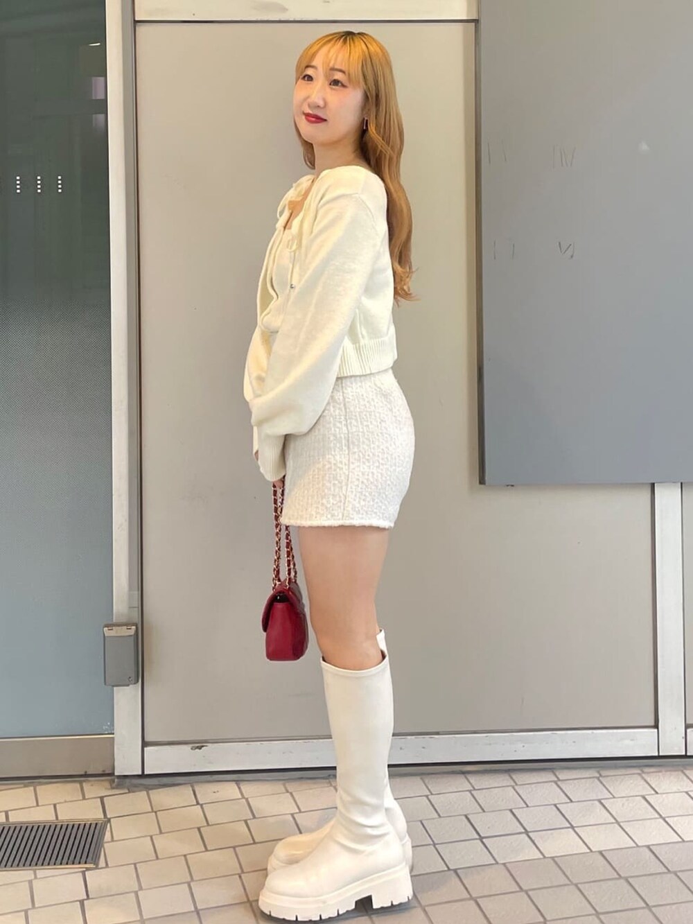 ホワイト系のニット/セーター、ホワイト系のその他パンツ、レッド系のショルダーバッグを着用したレディースの冬コーディネートの2枚目の写真