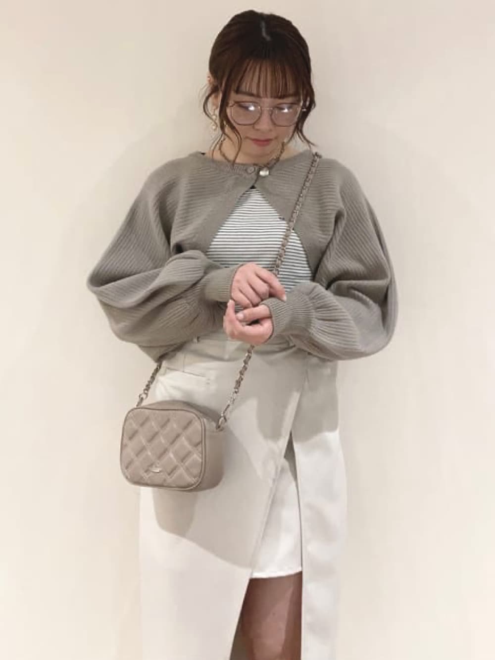 ホワイト系のスカート、ベージュ系のショルダーバッグ、ブラック系のカーディガン/ボレロを着用したレディースの冬コーディネートの2枚目の写真