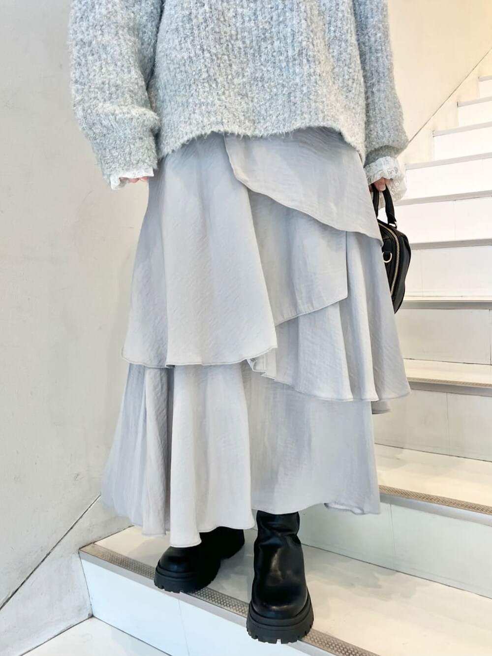 ブルー系のニット/セーター、ホワイト系のTシャツ/カットソー、グレー系のスカートを着用したレディースの冬コーディネートの4枚目の写真