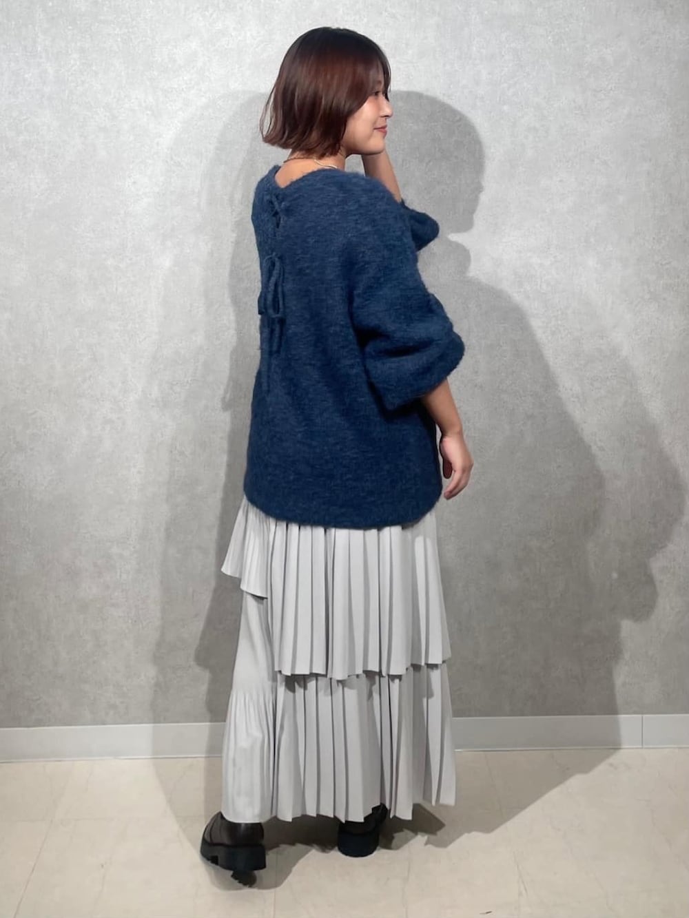 ブルー系のニット/セーター、グレー系のスカートを着用したレディースの秋コーディネートの3枚目の写真