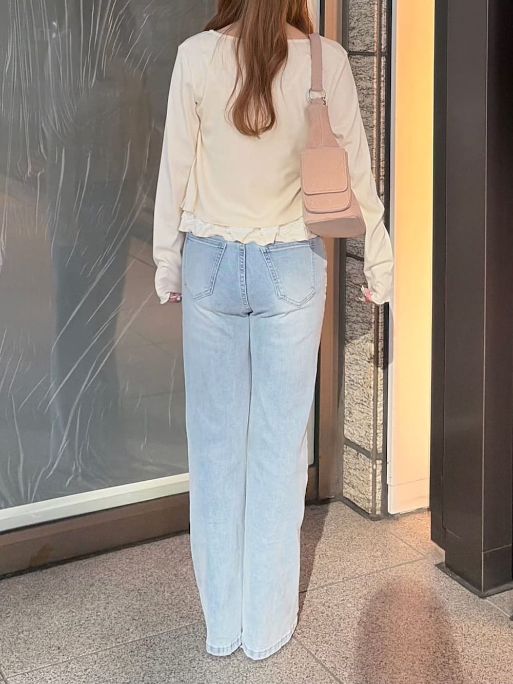 ホワイト系のTシャツ/カットソー、ブルー系のデニムパンツ、ベージュ系のショルダーバッグを着用したレディースの秋コーディネートの3枚目の写真