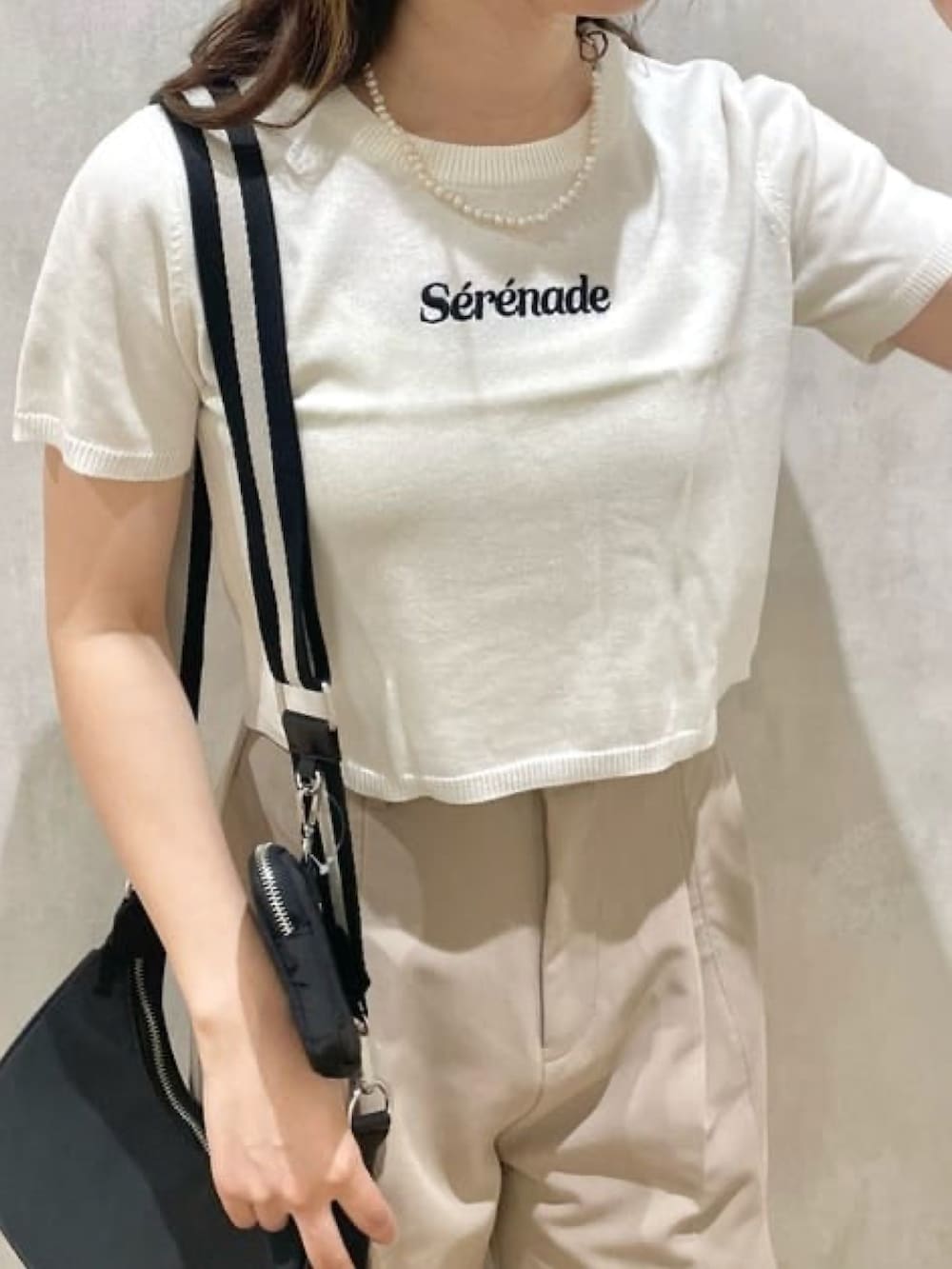 ホワイト系のニット/セーター、ベージュ系のその他パンツ、ブラック系のショルダーバッグを着用したレディースの夏コーディネートの2枚目の写真