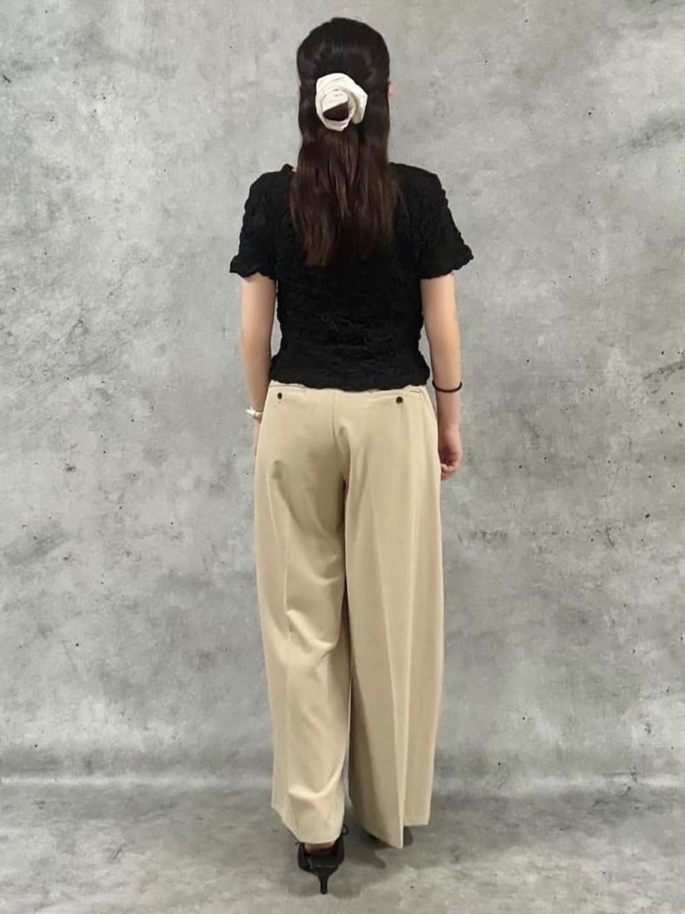ベージュ系のスラックス、ブラック系のTシャツ/カットソー、ブラック系のパンプスを着用したレディースの夏コーディネートの3枚目の写真