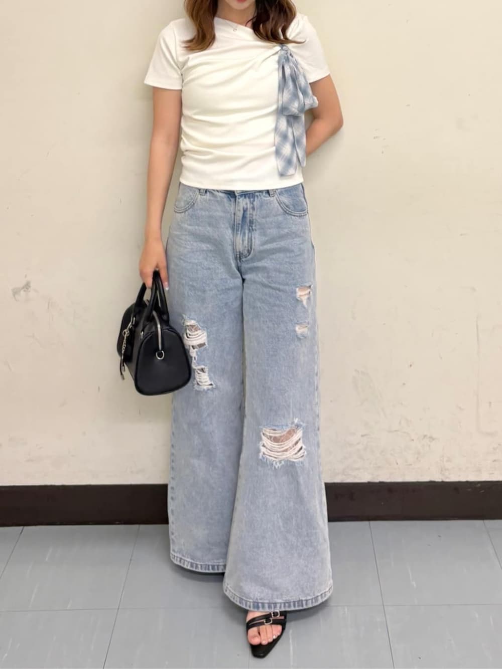 ブルー系のデニムパンツ、ブラック系のサンダル、ホワイト系のTシャツ/カットソーを着用したレディースの夏コーディネートの4枚目の写真