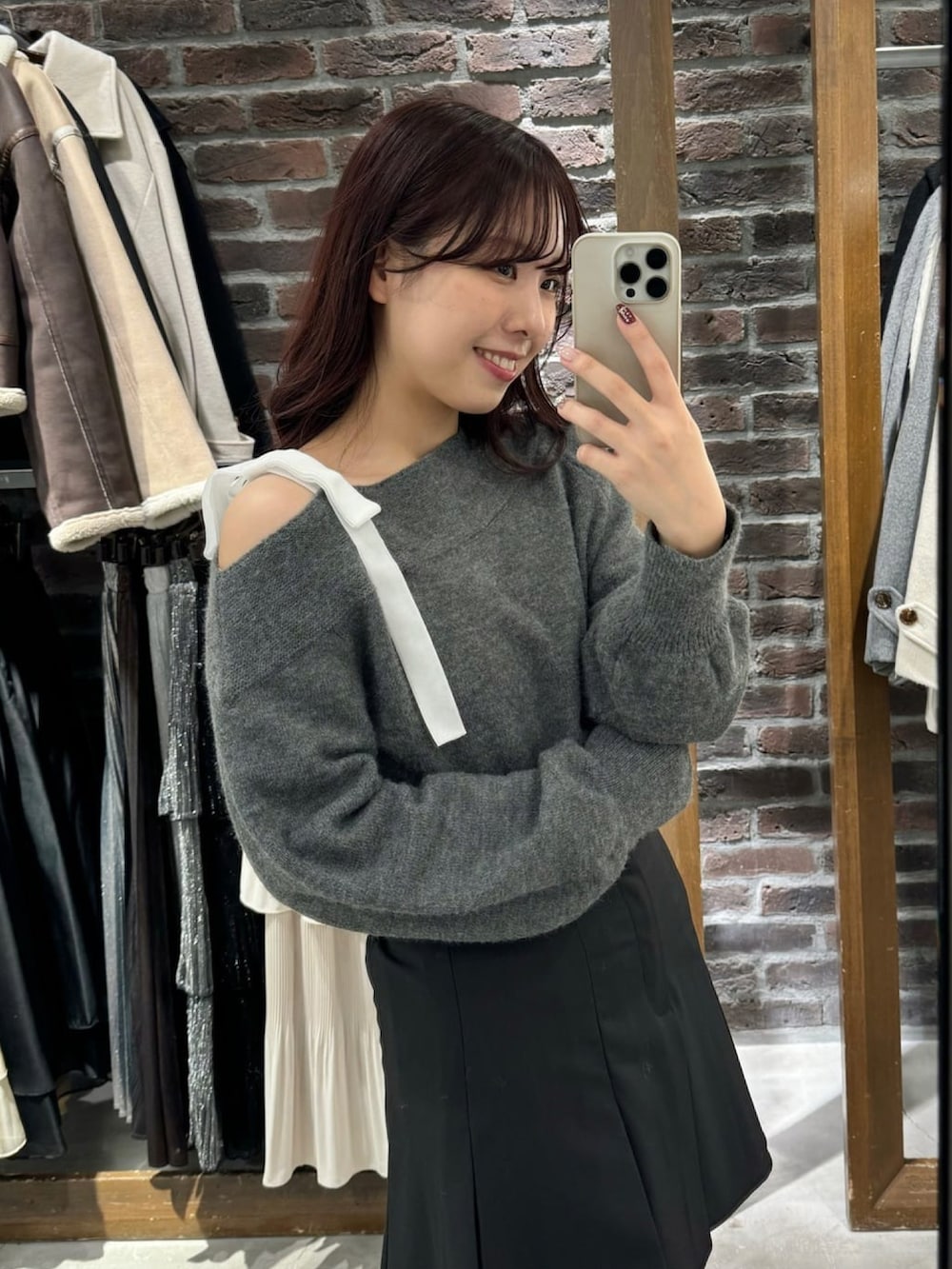 グレー系のニット/セーター、ホワイト系のショルダーバッグ、ブラック系のスカートを着用したレディースの冬コーディネートの2枚目の写真