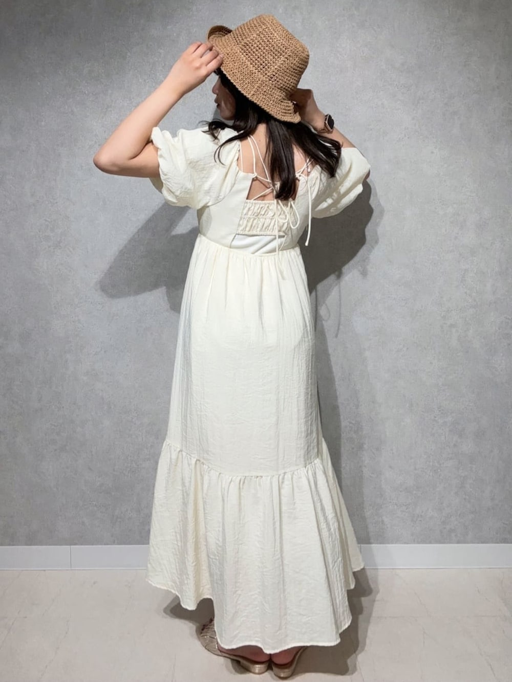 ホワイト系のワンピース、ゴールド系のサンダルを着用したレディースの夏コーディネートの2枚目の写真