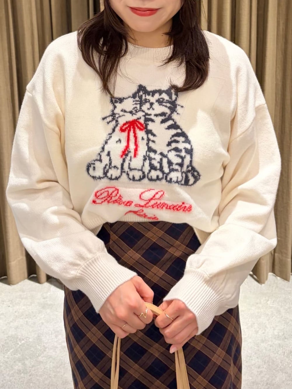 ブルー系のスカート、ホワイト系のニット/セーター、ベージュ系のイヤーマフを着用したレディースの冬コーディネートの3枚目の写真