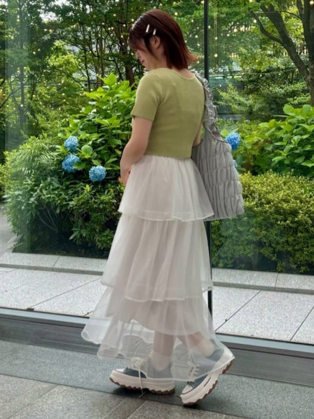 イエロー系のニット/セーター、ホワイト系のスカートを着用したレディースの夏コーディネートの2枚目の写真