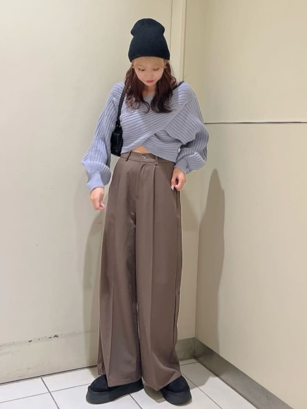 ホワイト系のニット/セーター、ブラウン系のスラックス、ブラック系のブーツを着用したレディースの冬コーディネートの2枚目の写真