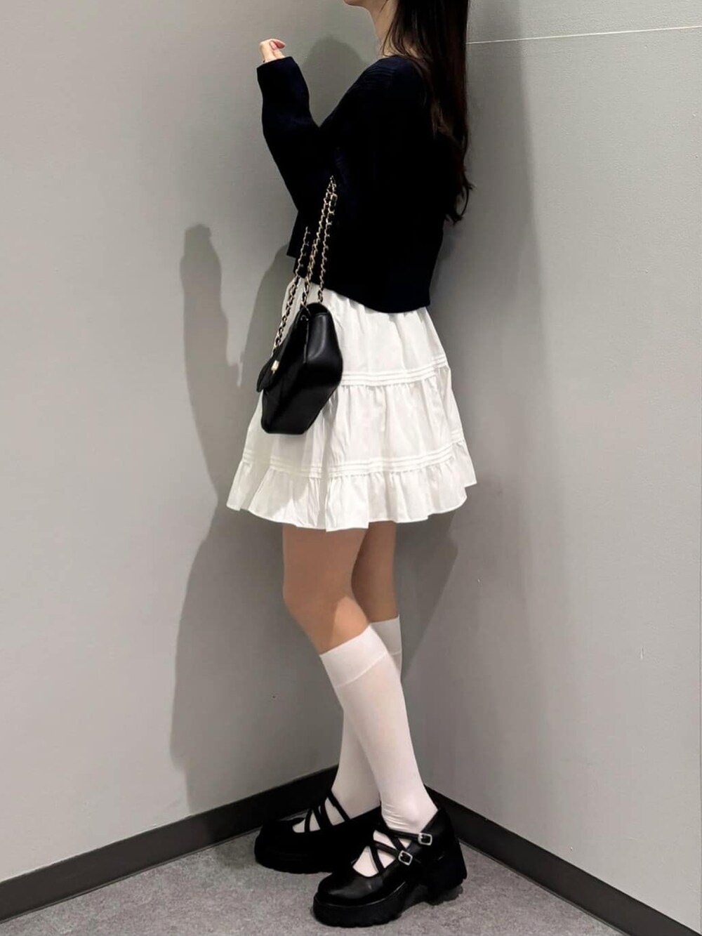 ブルー系のニット/セーター、ブラック系のショルダーバッグ、ホワイト系のスカートを着用したレディースの冬コーディネートの2枚目の写真