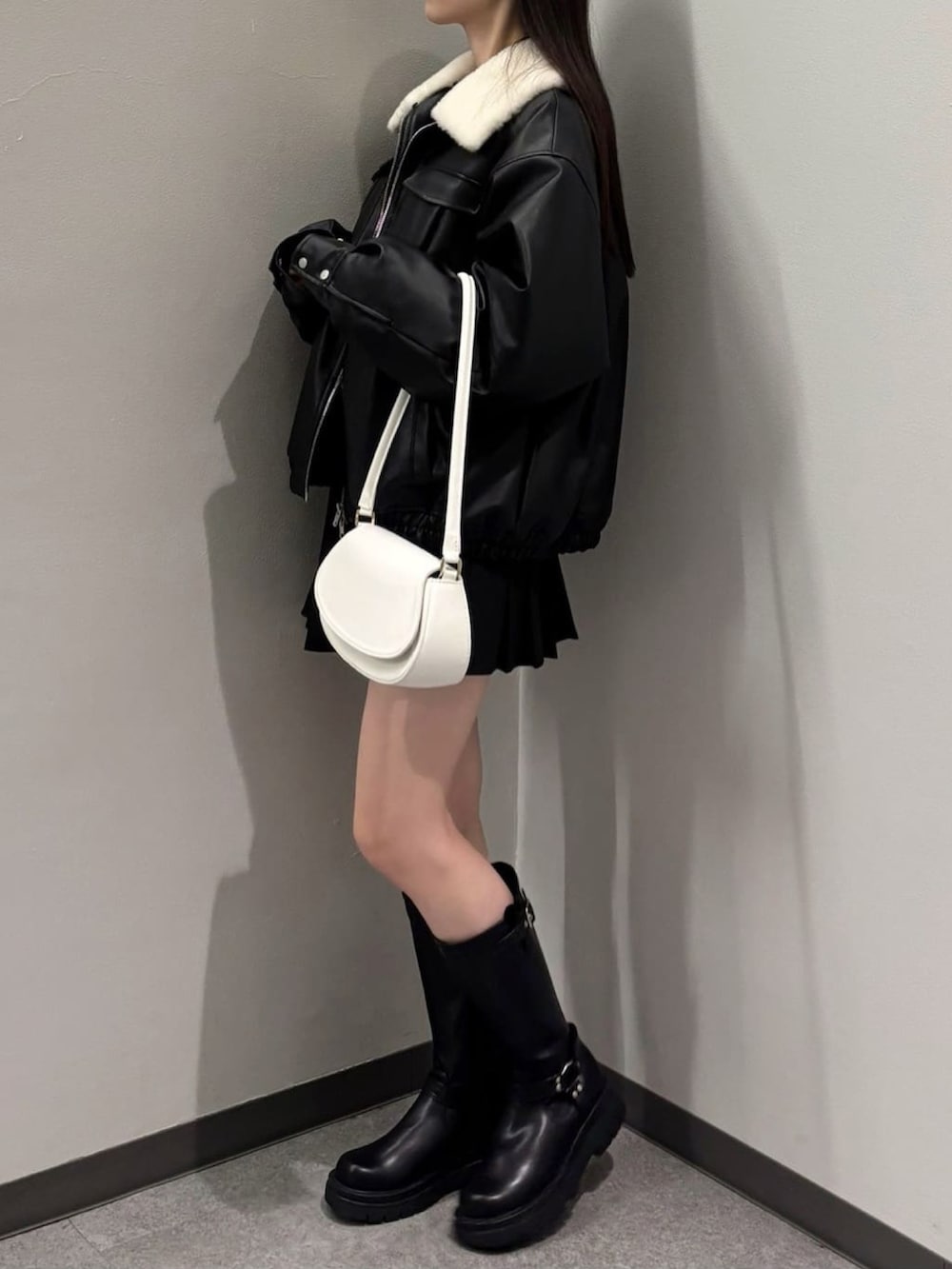 ブラック系のブルゾン、ブラック系のブーツ、ブラック系のスカートを着用したレディースの冬コーディネートの2枚目の写真