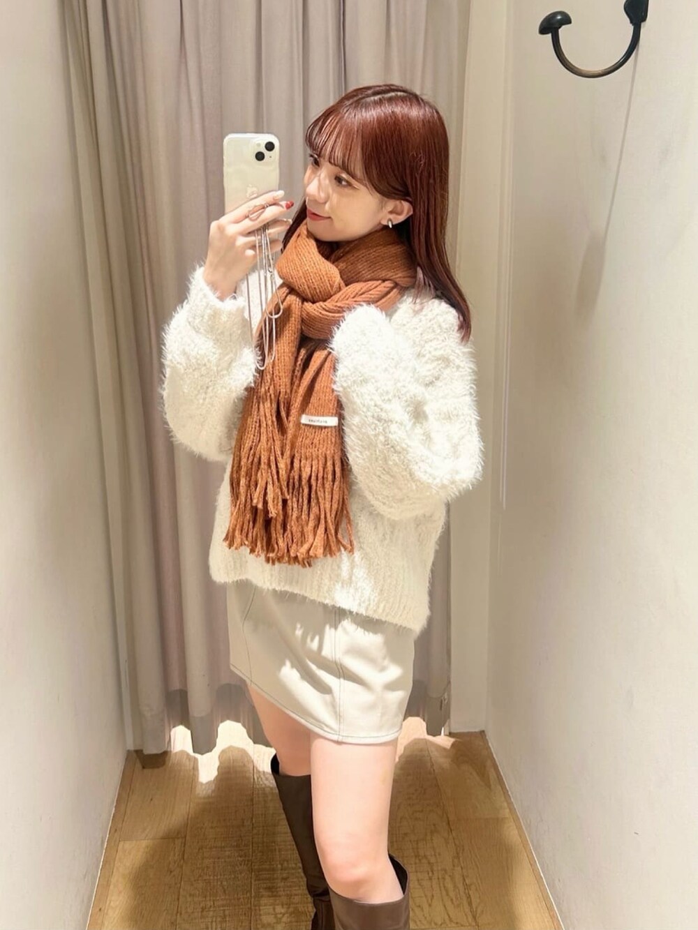 ホワイト系のニット/セーター、ホワイト系のスカート、ホワイト系のブーツを着用したレディースの冬コーディネートの2枚目の写真