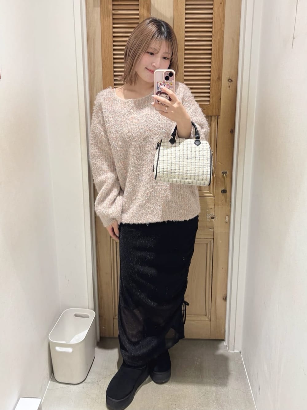 ピンク系のニット/セーター、ブラック系のスカート、ホワイト系のボストンバッグを着用したレディースの冬コーディネートの4枚目の写真