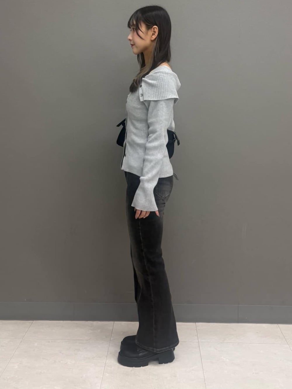 グレー系のデニムパンツ、グレー系のニット/セーター、ブラック系のハンドバッグを着用したレディースの秋コーディネートの2枚目の写真