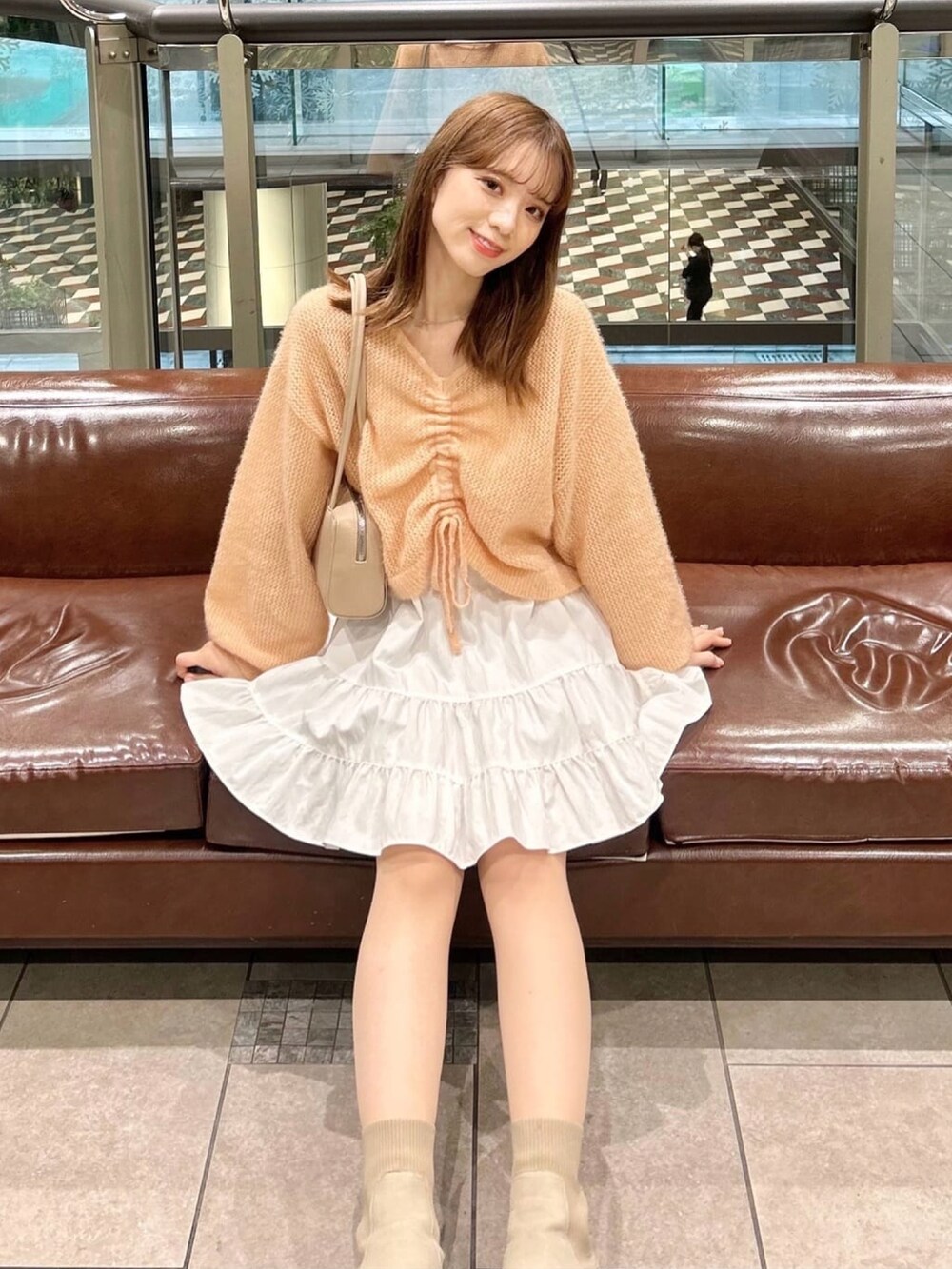 オレンジ系のニット/セーター、ホワイト系のスカートを着用したレディースの冬コーディネートの3枚目の写真