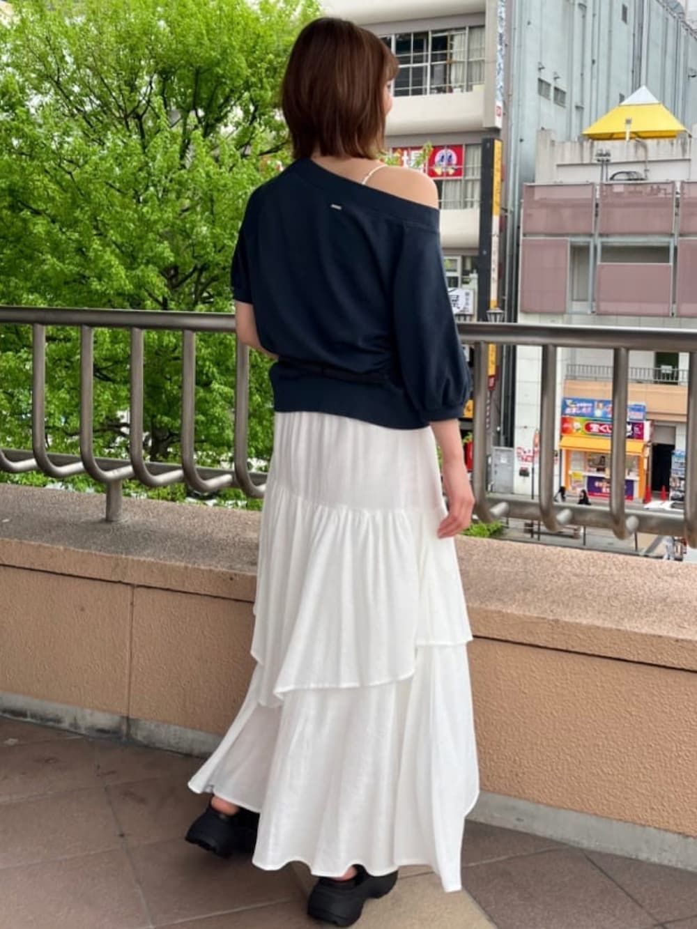 ブルー系のスウェット、ホワイト系のスカート、ブラック系のサンダルを着用したレディースの春コーディネートの2枚目の写真
